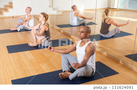 Hispanic man making yoga meditation in lotus pose with group 111624091