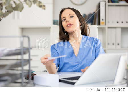 Woman physician giving recipe, sitting at table in office Woman physician giving recipe, sitting at table in office 111624307