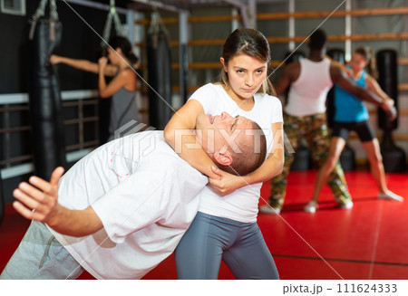 Woman exercising with man during group self-defence training 111624333