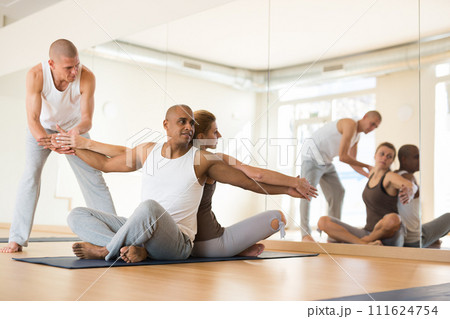 People practicing yoga with partner at studio People practicing yoga with partner at studio 111624754