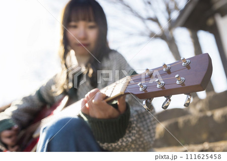 路上ライブでギターを弾く若い女性 111625458