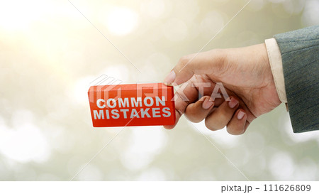 Business hand holding wooden block with 'common mistake' text Business hand holding wooden block with 'common mistake' text 111626809