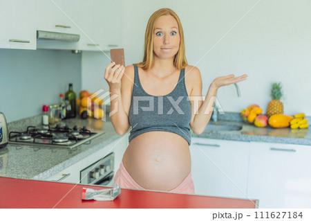 Contemplating the sweet dilemma, a pregnant woman ponders the decision to indulge in chocolate during pregnancy, weighing the delightful treat's potential impact on her maternal journey Contemplating the sweet dilemma, a pregnant woman ponders the decision to indulge in chocolate during pregnancy, weighing the delightful treat's potential impact on her maternal journey 111627184