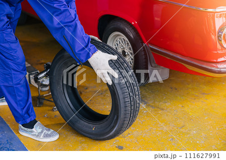 closeup garage mechanic worker replace car tyre change replace rubber wheels in auto service center concept closeup garage mechanic worker replace car tyre change replace rubber wheels in auto service center concept 111627991