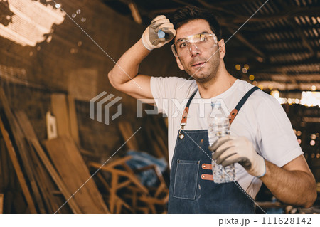 Tired stress carpenter man worker sweating hot workplace hardwork drinking water brake relax dehydrate in wood furniture workshop. Tired stress carpenter man worker sweating hot workplace hardwork drinking water brake relax dehydrate in wood furniture workshop. 111628142