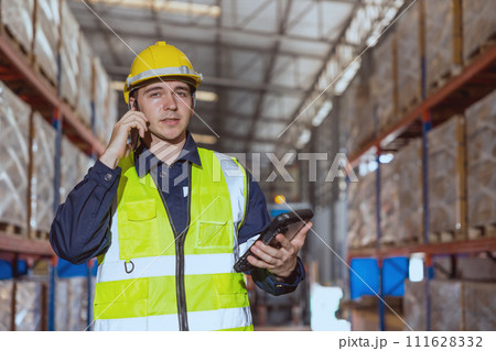 Warehouse worker using smartphone phone calling contact people in factory cargo storage area. 111628332