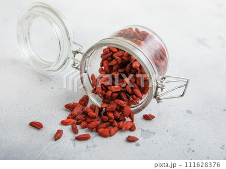 Glass jar with dried red sweet goji berries on white kitchen background. 111628376