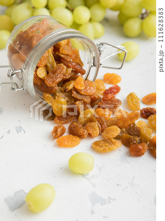 Green dried sweet raisins in glass jar on light background.Macro Green dried sweet raisins in glass jar on light background.Macro 111628383