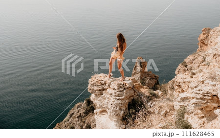 Woman travel sea. Happy tourist enjoy taking picture outdoors for memories. Woman traveler looks at the edge of the cliff on the sea bay of mountains, sharing travel adventure journey Woman travel sea. Happy tourist enjoy taking picture outdoors for memories. Woman traveler looks at the edge of the cliff on the sea bay of mountains, sharing travel adventure journey 111628465