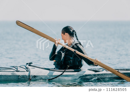Woman sea kayak. Happy smiling woman in kayak on ocean, paddling with wooden oar. Calm sea water and horizon in background. Active lifestyle at sea. Summer vacation. Woman sea kayak. Happy smiling woman in kayak on ocean, paddling with wooden oar. Calm sea water and horizon in background. Active lifestyle at sea. Summer vacation. 111628505