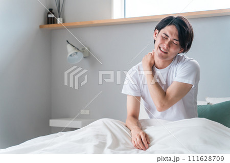 朝寝起きに肩こりに悩む若いアジア人男性（疲労・寝違え・四十肩） 111628709