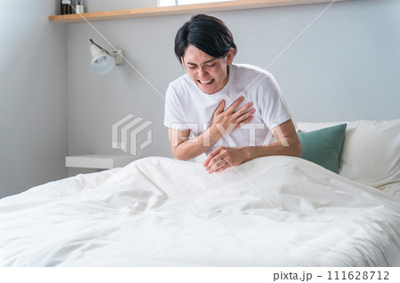 ベッドの上で胸を苦しがる急病の男性(苦しい・発作・心筋梗塞・心臓発作・動悸・狭心症) ベッドの上で胸を苦しがる急病の男性(苦しい・発作・心筋梗塞・心臓発作・動悸・狭心症) 111628712