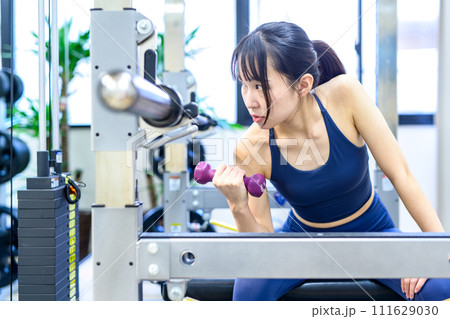 パーソナルジムで体を鍛える若い女性 ダンベルコンセントレーションカール 筋トレ女子 ワークアウト パーソナルジムで体を鍛える若い女性 ダンベルコンセントレーションカール 筋トレ女子 ワークアウト 111629030