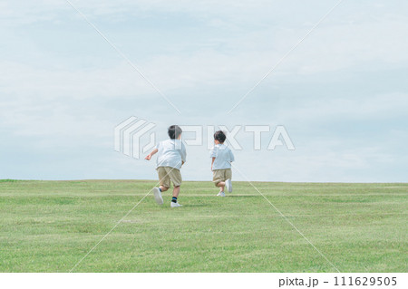 芝生の丘で追いかけっこする活発な子供達・兄弟・走る 111629505