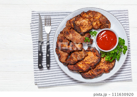 fried juicy pork steaks with ketchup on plate 111630920