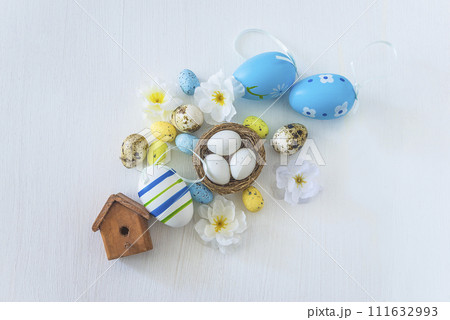 Happy easter holidays concept; Easter eggs, birdnest with eggs and flowers on a white background; top view Happy easter holidays concept; Easter eggs, birdnest with eggs and flowers on a white background; top view 111632993