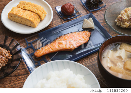 鮭の西京焼きと卵焼きと納豆と豆腐と油揚げとワカメのお味噌汁の梅干しなど家庭的な和朝食 111633260