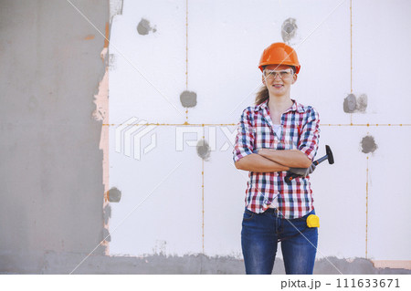 The female worker stands in front of a wall insulated with foam plastic The female worker stands in front of a wall insulated with foam plastic 111633671