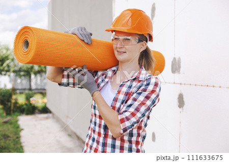 The woman with rolls of reinforcing fiberglass. Insulation of the house with polyfoam board on the facade The woman with rolls of reinforcing fiberglass. Insulation of the house with polyfoam board on the facade 111633675