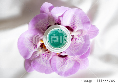 Natural liquid laundry detergent with a floral scent on a background of satin fabric. Natural liquid laundry detergent with a floral scent on a background of satin fabric. 111633765
