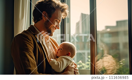 a dad tenderly holds his baby in his arms. 111636985