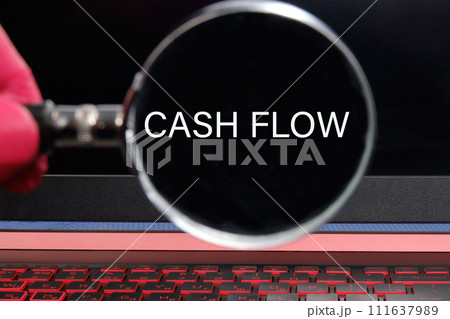 Cash flow text written through a magnifying glass on a black laptop screen Cash flow text written through a magnifying glass on a black laptop screen 111637989