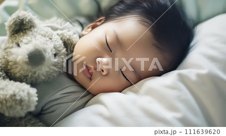 portrait of a charming sleeping baby with a cute teddy bear on a comfortable bed. 111639620