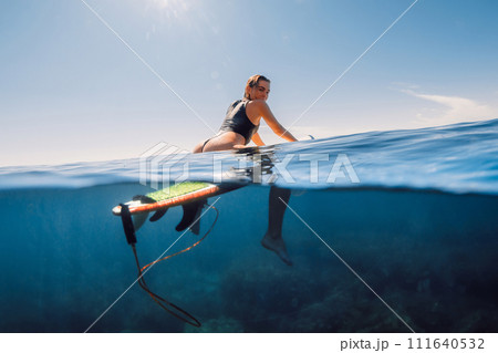 Surfer woman in sexy bikini on surfboard in clear ocean. Water activity lifestyle on summer vacation 111640532