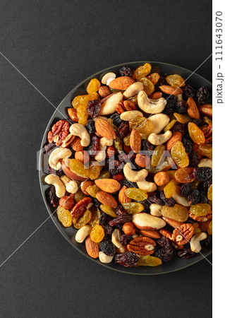 Mix of dried nuts and raisins on a black background. 111643070