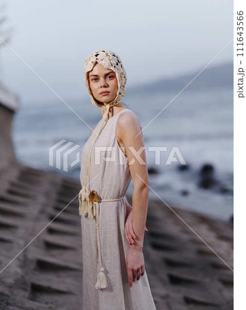 Pretty Young Woman in a Blue Dress, Posing on the Beach, with Beautiful Sea as Background 111643566