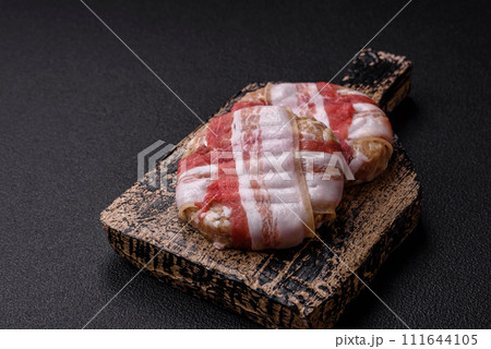 Round minced chicken or pork cutlet wrapped in bacon with salt, spices and herbs Round minced chicken or pork cutlet wrapped in bacon with salt, spices and herbs 111644105