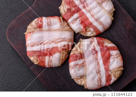 Round minced chicken or pork cutlet wrapped in bacon with salt, spices and herbs 111644122