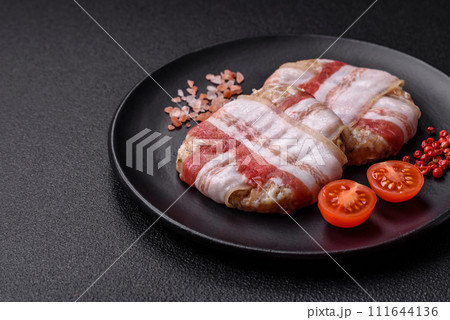 Round minced chicken or pork cutlet wrapped in bacon with salt, spices and herbs Round minced chicken or pork cutlet wrapped in bacon with salt, spices and herbs 111644136