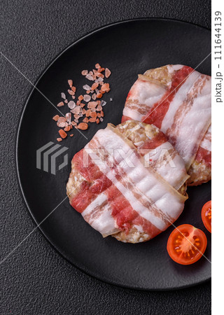 Round minced chicken or pork cutlet wrapped in bacon with salt, spices and herbs 111644139