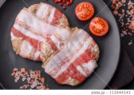 Round minced chicken or pork cutlet wrapped in bacon with salt, spices and herbs Round minced chicken or pork cutlet wrapped in bacon with salt, spices and herbs 111644143