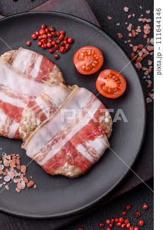 Round minced chicken or pork cutlet wrapped in bacon with salt, spices and herbs 111644146