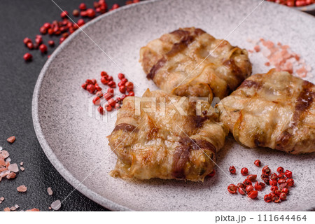 Round minced chicken or pork cutlet wrapped in bacon with salt, spices and herbs 111644464