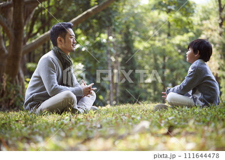 young asian father having a pleasant conversation with son outdoors young asian father having a pleasant conversation with son outdoors 111644478