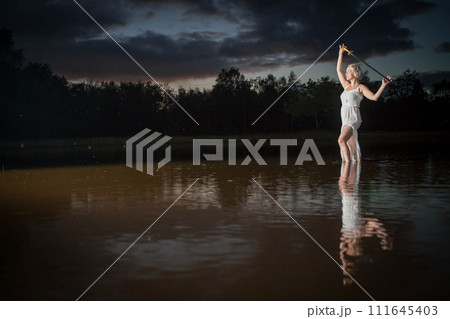 Ethereal Woman Holding sword by Lakeside at Dusk Ethereal Woman Holding sword by Lakeside at Dusk 111645403