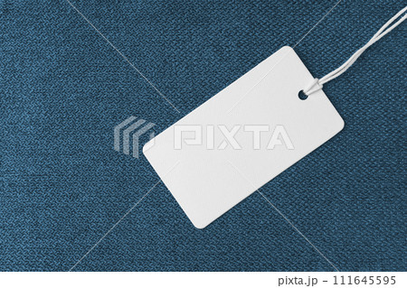 Textile background, blue coarse fabric texture with white empty clothing tag 111645595
