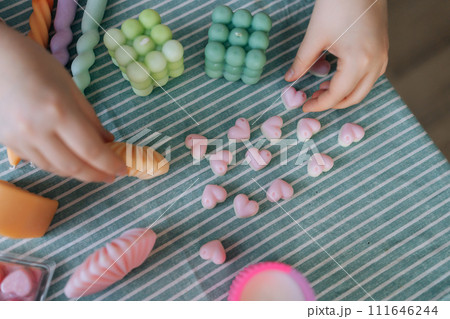 Top view of unrecognizable female artisan sitting at desk with finished various candles after create. Process of making handmade natural scented candle. Creative occupation of making DIY candles. 111646244