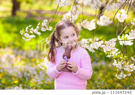 Kids on Easter egg hunt in blooming garden. 111647248