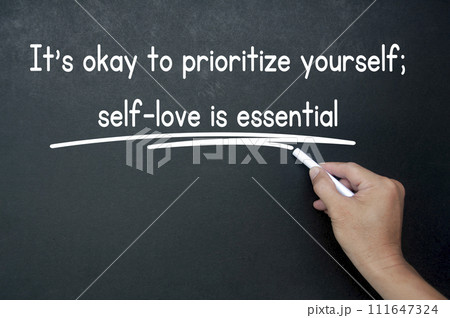 Hand writing It is okay to prioritize yourself affirmation on black board. Affirmation concept. Hand writing It is okay to prioritize yourself affirmation on black board. Affirmation concept. 111647324