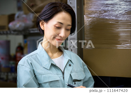 倉庫で棚卸しする作業着の女性 111647420