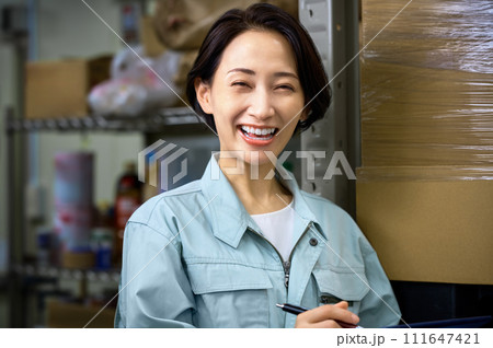 倉庫で棚卸しする作業着の女性 倉庫で棚卸しする作業着の女性 111647421
