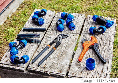 Compression fittings for connecting HDPE pipes lie on table next to hand tools. 111647484