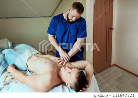 Chest massage for young man at home by mobile massage therapist. 111647521