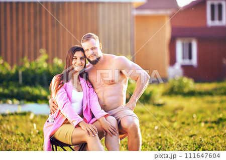 Portrait of European married couple in their 20s sitting in vegetable garden near their house. 111647604