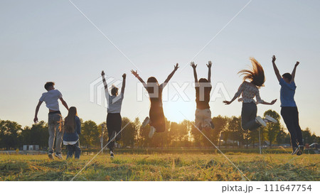Group of five happy friends jumps at sunset time on background mountains. 111647754