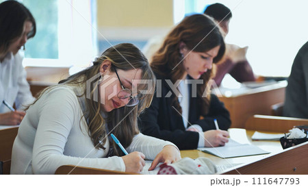 Girl students writing math formulas in a notebook. 111647793